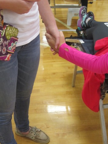 Volunteer Kayla Morgan holds the hand of a brave donating friend.