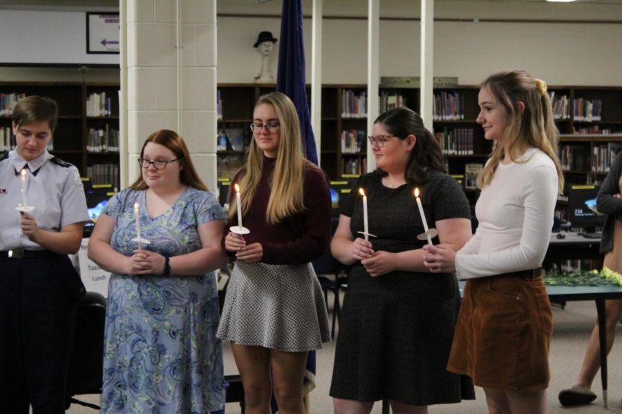 New inductees hold candles at the ceremony.